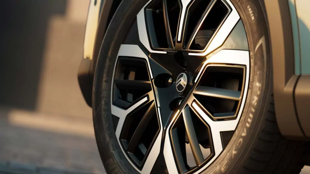 Nahaufnahme eines modernen Pkw-Leichtmetallrads mit einem eleganten, geometrischen schwarz-silbernen Design. Der Reifen mit der Aufschrift Primacy ist sauber, und die Oberfläche des Rades reflektiert das Sonnenlicht, wodurch das elegante Muster hervorgehoben wird.