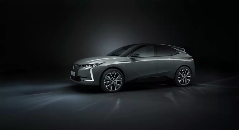 Ein schnittiger, moderner grauer Geländewagen mit scharfen Linien und großen Leichtmetallrädern wird in einer dunklen Studiokulisse präsentiert, die von sanften Scheinwerfern beleuchtet wird, die sein elegantes Außendesign hervorheben.