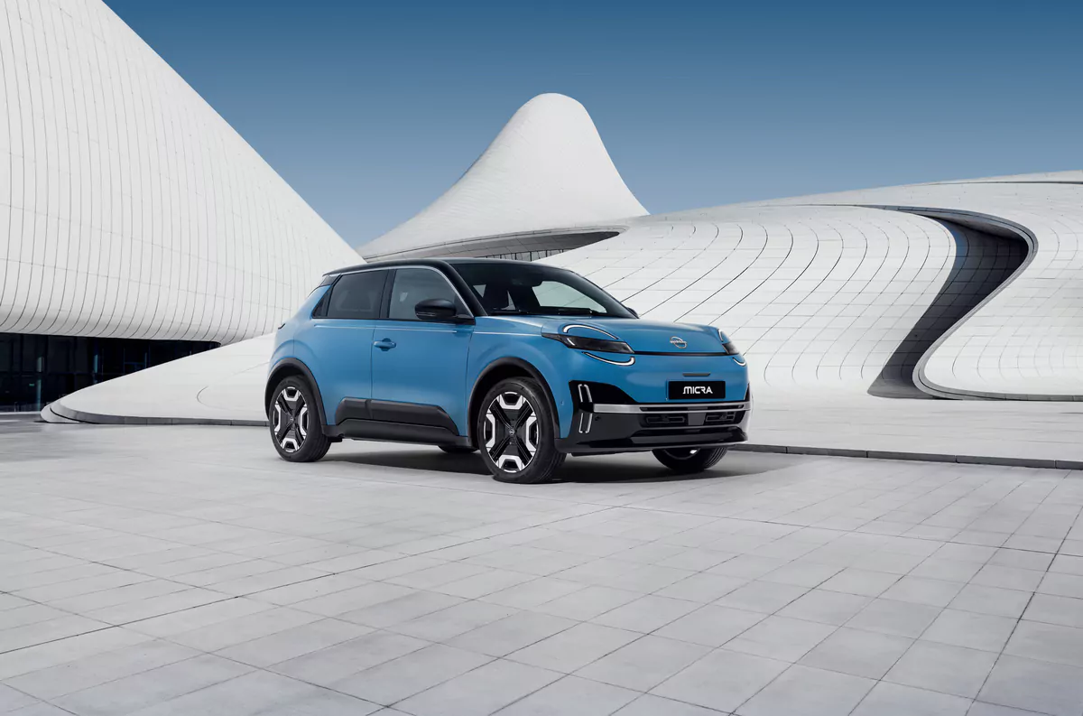 Ein blaues Ora Next Elektroauto ist auf einem modernen, offenen Platz mit futuristischer, weiß geschwungener Architektur im Hintergrund unter einem klaren blauen Himmel geparkt.