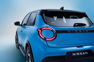 Rückansicht eines blauen Nissan Micra vor einem blauen Hintergrund mit Farbverlauf, der das runde LED-Rücklicht, die schlanken Linien und das Nissan-Logo auf dem Kofferraum hervorhebt.
