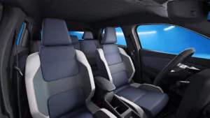 Innenansicht eines Autos mit modernen blauen und grauen Sitzen, einer zentralen Armlehne und einem sauberen Armaturenbrett, alles vor einem hellblauen Hintergrund, der durch die Fenster zu sehen ist.