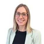 Eine Frau mit glattem blondem Haar und Brille lächelt in die Kamera. Sie trägt einen hellen Blazer über einem schwarzen Oberteil, vor einem schlichten weißen Hintergrund - perfekt für Auto Mattern Karriere Jobs wie Serviceassistentin oder Bewerbung in Vollzeit.