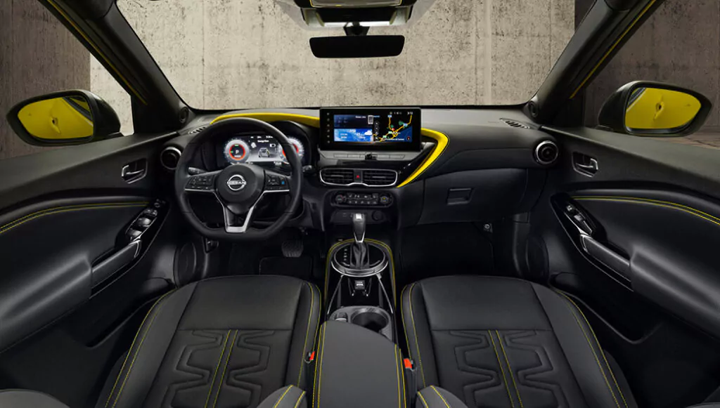 Innenansicht eines modernen Nissan-Fahrzeugs mit schwarzen Ledersitzen mit gelben Nähten, einem digitalen Armaturenbrett, einem zentralen Touchscreen-Display und einem sportlich-eleganten Design mit gelben Akzenten auf dem Armaturenbrett und den Türen.