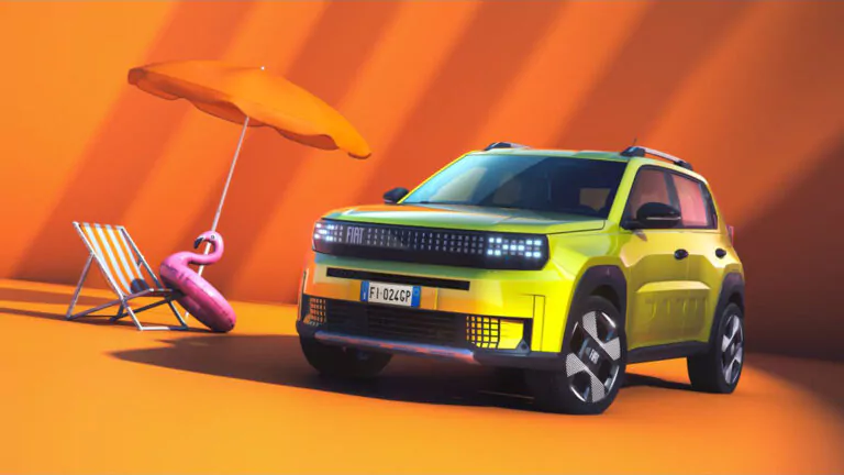 Ein leuchtend gelber Fiat SUV ist auf einer orangefarbenen Fläche neben einem Liegestuhl, einem rosa Flamingo und einem orangefarbenen Sonnenschirm geparkt, vor einem orangefarbenen Hintergrund mit dramatischen Schatten.