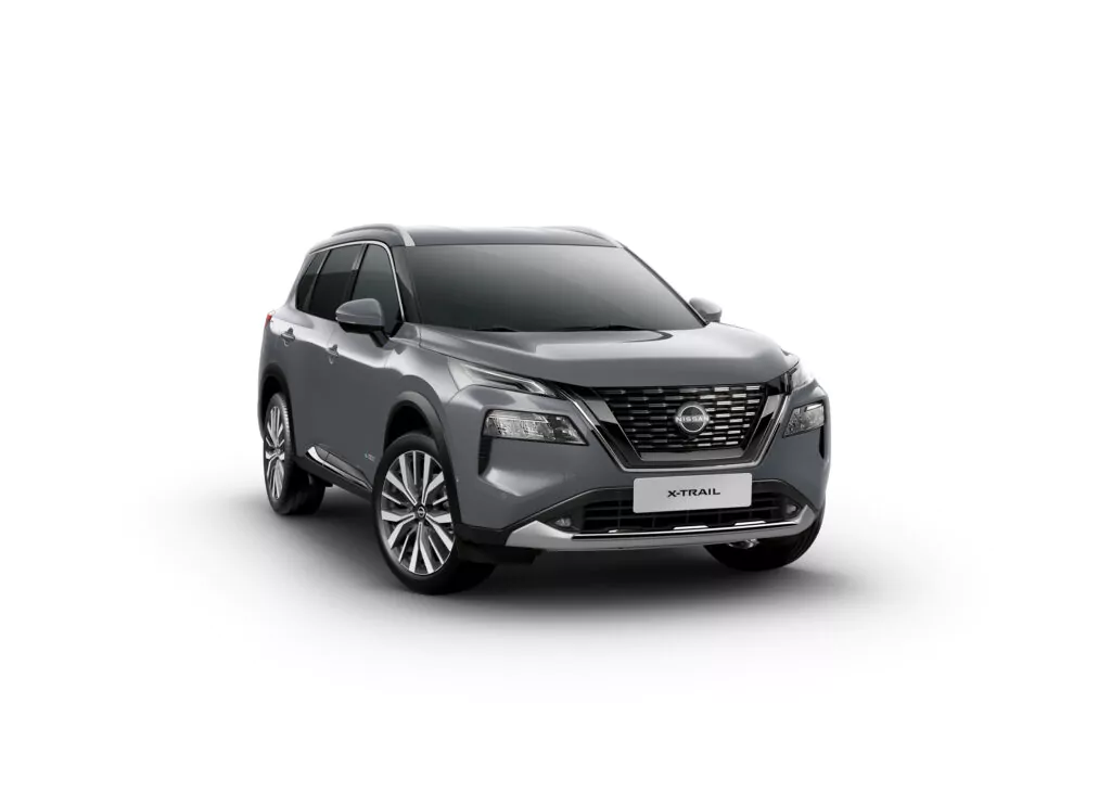Ein grauer Nissan X-Trail N-Trek Angebot SUV ist auf einem schlichten weißen Hintergrund geparkt, von vorne links gesehen. Das Fahrzeug verfügt über moderne Scheinwerfer, einen markanten Kühlergrill und Leichtmetallfelgen.
