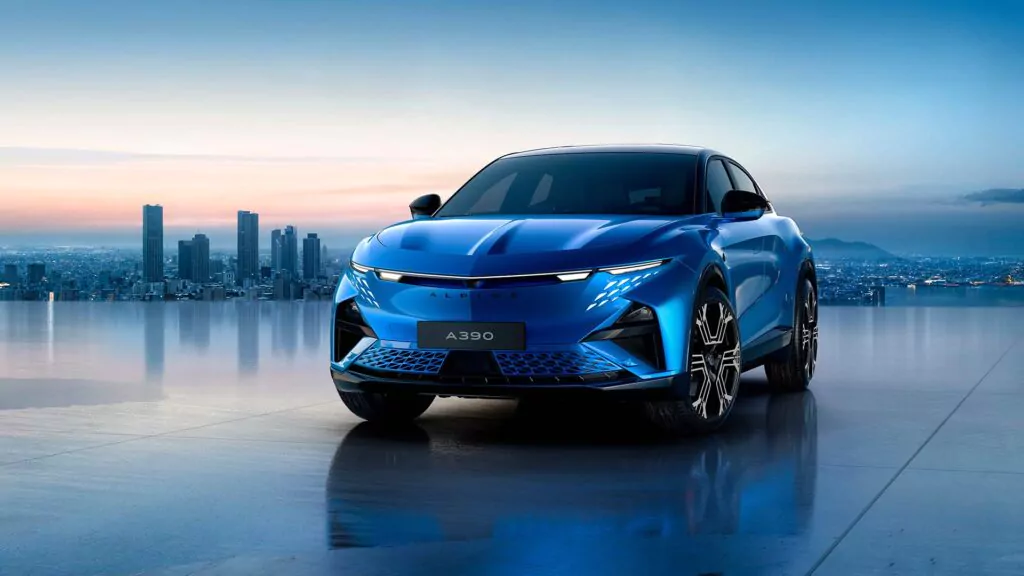 Eine schnittige blaue Alpine A390 parkt auf einer glänzenden Oberfläche mit einer Stadtsilhouette und Wolkenkratzern im Hintergrund, unter einem klaren Himmel bei Sonnenuntergang - perfekt für die Präsentation während des Aktionswochenendes.