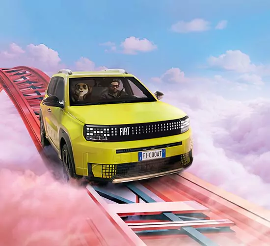 Ein gelber Fiat Grande mit einem Fahrer und einem großen Pandabären auf dem Beifahrersitz fährt auf einer Achterbahnstrecke hoch über rosa Wolken unter blauem Himmel.
