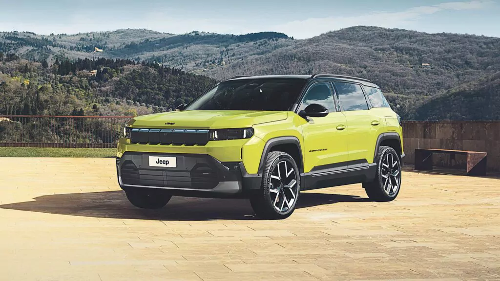 Ein leuchtend gelber Jeep-Geländewagen ist während des Aktionswochenendes auf einer großen Steinterrasse geparkt, mit baumbewachsenen Hügeln und Bergen im Hintergrund unter einem klaren Himmel.