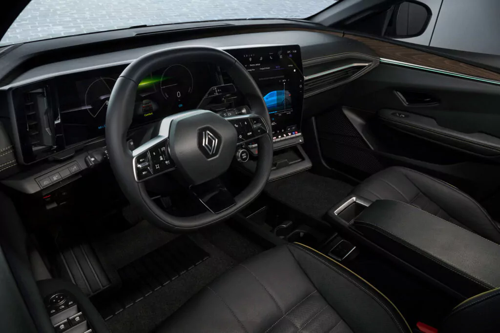 Der Innenraum eines modernen Fahrzeugs mit digitalem Kombiinstrument, großem Touchscreen-Display, Lenkrad mit Renault Schriftzug, schwarzen Ledersitzen und eleganten Akzenten am Armaturenbrett.