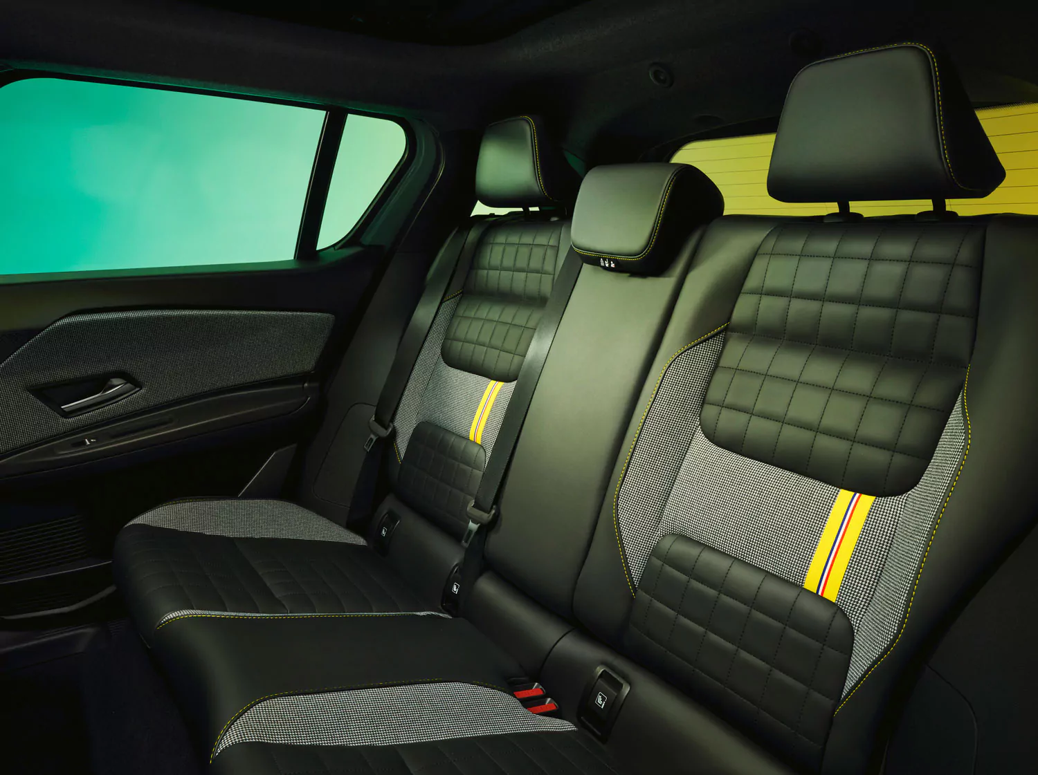 Das Bild zeigt den Rücksitz eines modernen Fahrzeugs mit schwarzem Steppleder, grauen Stoffeinsätzen und gelb-rot gestreiften Akzenten an den Sitzlehnen. Der Innenraum wirkt sauber und stilvoll mit sichtbaren Kopfstützen.