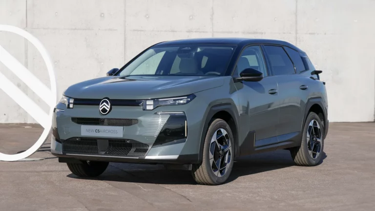 Ein metallicgrauer Citroën C3 Aircross SUV parkt auf einer gepflasterten Fläche vor einer schlichten Betonwand und präsentiert sein modernes Design und seine kantigen Frontscheinwerfer.