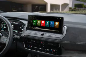 Nahaufnahme eines Nissan Qashqai N-Connecta Armaturenbretts mit einem großen Touchscreen mit App-Symbolen, Klimabedienelementen darunter und einem Teil des Lenkrads. Der Innenraum besticht durch sein modernes und schlankes Design.