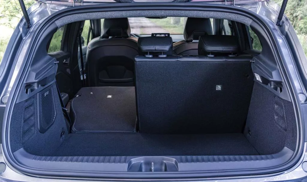 Offener Kofferraum eines Renault Clio mit umgeklapptem Rücksitz und aufgestelltem Rücksitz, der den erweiterten Laderaum und die schwarze Innenausstattung zeigt. Perfekt für das Renault Clio Leasing: Diese Ansicht von außen unterstreicht die vielseitigen Ablagemöglichkeiten.