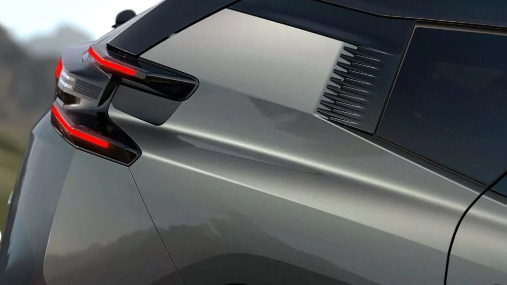 Nahaufnahme der Rückseite eines modernen grauen Autos, die das kantige Rücklichtdesign, die scharfen Karosserielinien und die kleinen aerodynamischen Öffnungen in der Nähe der Fenster hervorhebt.