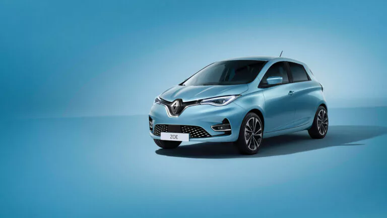 Ein hellblaues Renault Zoe-Elektroauto ist auf einem nahtlosen blauen Hintergrund geparkt und leicht nach rechts ausgerichtet. Der Kühlergrill und die Scheinwerfer des Autos sind deutlich zu sehen und heben die Renault ZOE Batterie Aktion mit dem Nummernschild ZOE hervor.