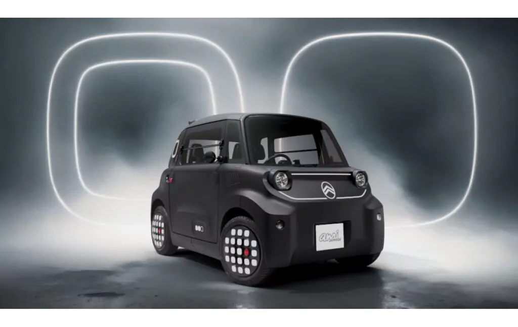 Ein kompaktes, schwarzes Citroën Ami-Elektroauto wird in einer futuristischen Umgebung mit beleuchteten quadratischen Lichtformen und einer nebligen Atmosphäre im Hintergrund gezeigt.