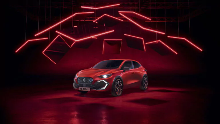 Ein schnittiges rotes Auto, der neue Renault Clio, wird unter dramatischen roten Neonlichtern und darüber hängenden geometrischen Tafeln ausgestellt, die eine moderne und futuristische Atmosphäre schaffen.