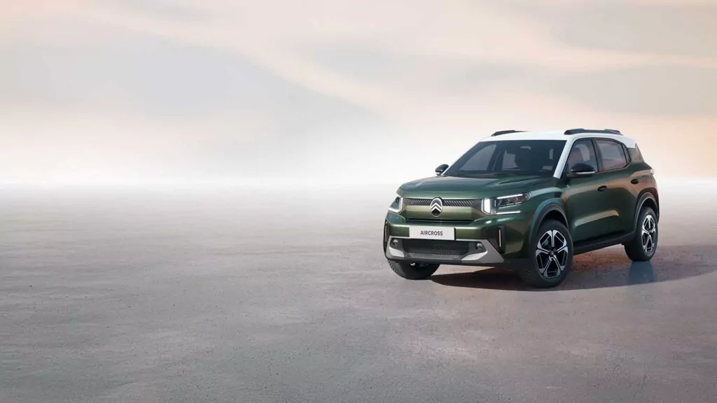 Ein dunkelgrüner Citroën Geländewagen ist auf einer leeren, glatten Fläche geparkt, mit einem weichen, pastellfarbenen Himmel im Hintergrund. Das Auto steht auf der rechten Seite, während auf der linken Seite reichlich Platz ist.