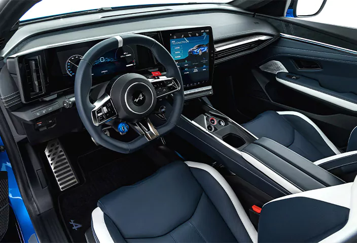 Innenraum eines Alpine A390 mit blau-weißem Lenkrad, digitalen Anzeigen im Armaturenbrett sowie dunkelblauen und weißen Ledersitzen.