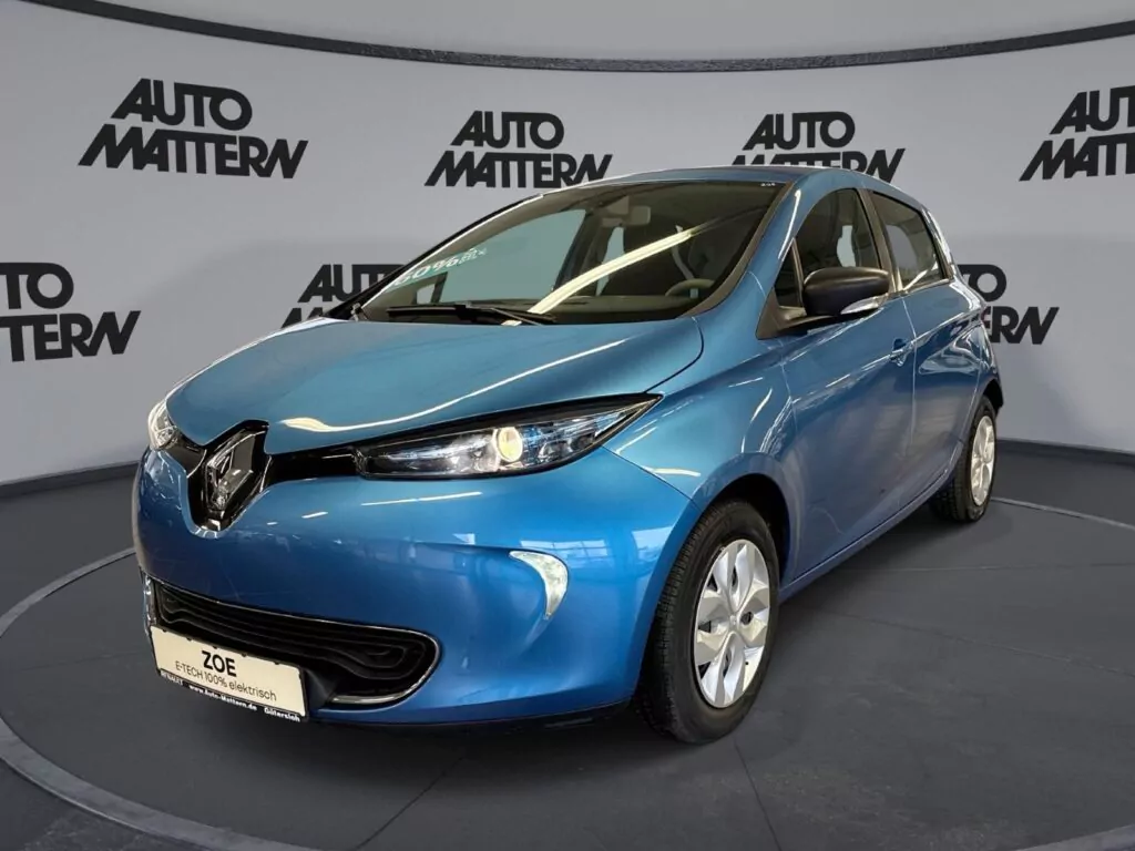 Ein blaues Renault Zoe-Elektroauto steht in einem Ausstellungsraum mit Auto Mattern-Logos an den geschwungenen Wänden im Hintergrund und lädt die Besucher ein, beim Tag der offenen Tür März 2026 mehr zu entdecken. Das Auto ist auf einer grauen, runden Plattform geparkt.