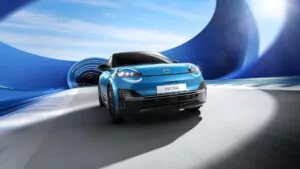 Ein blaues Nissan Micra-Elektroauto fährt durch einen futuristischen, blau beleuchteten Tunnel, wobei Bewegungsunschärfe Geschwindigkeit und eine dynamische, moderne Umgebung suggeriert.