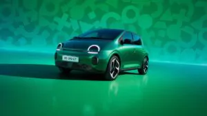 Ein grüner Kleinwagen mit runden LED-Scheinwerfern ist auf einer glänzenden grünen Fläche geparkt, auf deren Hintergrund geometrische Muster in verschiedenen Grüntönen zu sehen sind.