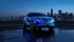 Ein elegantes blaues Elektroauto ist auf einem nächtlichen Dach geparkt, mit einer Stadtsilhouette und beleuchteten Wolkenkratzern im Hintergrund.