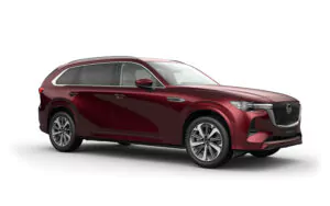 Ein roter Mazda CX-90 Geländewagen wird von vorne gezeigt, mit seinem schnittigen Design, den Chromverzierungen, den großen Rädern und den getönten Scheiben vor einem schlichten weißen Hintergrund.