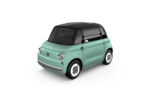 Ein kompaktes Elektroauto im Retrostil mit mintgrüner Karosserie und schwarzem Dach, gesehen von vorne links auf weißem Hintergrund.