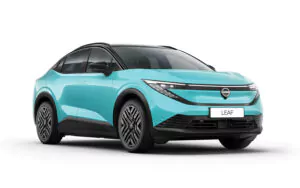 Ein türkisfarbenes, modernes Elektroauto mit schwarzen Akzenten und schlanken, kantigen Scheinwerfern, gezeigt aus einem Winkel von vorne. Auf dem vorderen Nummernschild steht LEAF.