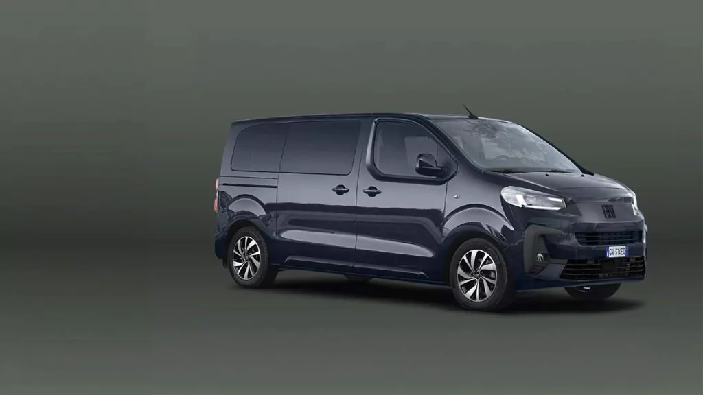 Ein dunkelblauer Transporter ist vor einem schlichten, neutralen Hintergrund nach rechts gerichtet abgebildet. Der Transporter hat getönte Scheiben, Leichtmetallfelgen und ein modernes Design. Das Bild ist gut ausgeleuchtet und hebt die äußeren Merkmale des Fahrzeugs hervor.