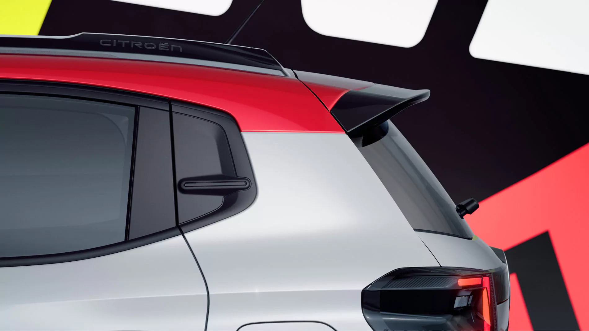Nahaufnahme der Rückseite eines weißen Autos mit rotem Dach und schwarzem Spoiler, im Hintergrund sind auffällige, farbenfrohe geometrische Formen zu sehen.