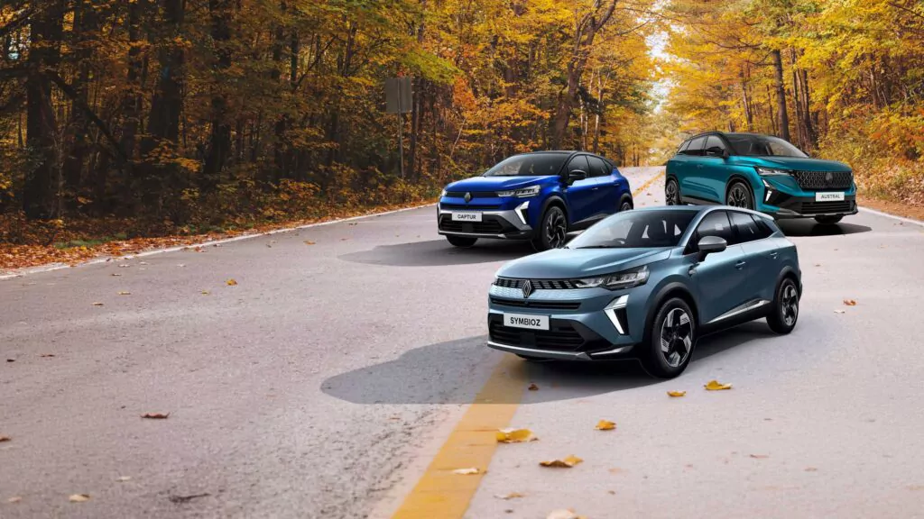 Drei Renault-Fahrzeuge – der Captur, der Austral und der Symbioz – stehen im Rahmen der Renault Herbst Deals auf einer kurvenreichen Straße, die von herbstlich gefärbten Bäumen gesäumt war.